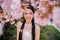 Portrait of young woman in park with blooming sakura trees