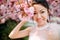 Portrait of young woman in park with blooming sakura trees