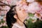 Portrait of young woman in park with blooming sakura trees