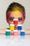 Portrait of young woman posing at the table with pyramid of small cans of paint