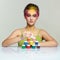 Portrait of young woman posing at the table with pyramid of small cans of paint