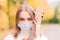 Portrait young woman in protective mask playing ukulele guitar in autumn park, healthy travel