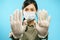 Portrait of a young woman in protective medical mask and gloves showing stop gesture. Social distancing and individual protection