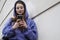 Portrait of a young woman in a purple hooded sweat using her smartphone
