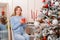 Portrait of a young woman sitting with a mug in her hands next to a Christmas tree