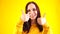 Portrait of young woman smiling and showing thumbs up on yellow background. Close up of happy brunette in yellow hoodie