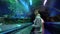 Portrait of young woman standing on moving walkway going through tunnel in oceanarium. Girl enjoying view of magnificent