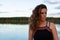 Portrait of young woman standing next to a lake wearing summery black dress looking beyond