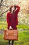 Portrait of a young woman with suitcase near blooming tree