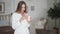 Portrait of young woman uses phone and drinks coffee or tea at kitchen