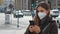 Portrait of young woman using smartphone wearing FFP2 KN95 protective mask and winter jacket outdoors