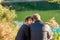 Portrait of young woman watching in camera with near sitting her lover. Couple hugging and relaxing near forest lake. Love