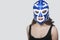 Portrait of a young woman wearing wrestling mask over gray background