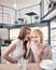 Portrait of young woman whispering into female friend\'s ear in cafe