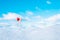 Portrait of young woman in white clothes with red heart balloon walking on snow cover with blue cloudy sky on background