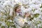 Portrait of the young woman among white colors of a rhododendron of Shlippenbakh