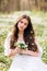 Portrait of a young woman in a white dress with primroses. A girl in the spring forest. White anemones in long brown hair