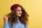 Portrait of a young woman with woolen hat in a studio on a yellow background.