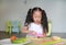 Portraits Asian children slicing cucumber vegetable on chopping board at play room. Kid play chef cooking