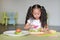 Portraits Asian children slicing cucumber vegetable on chopping board at play room. Kid play chef cooking