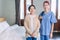 Portraits of Asian woman nurse wearing scrubs standing with Senior Asian woman in the bedroom. Caregiver visit at home.