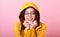 Portraits of a young girl in a yellow raincoat with a hood on her head in glasses, snuggles up to her hands because of the heat on