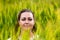 Portraot of young woman in rye field through grass