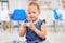 Portrat of one adorable little caucasian girl sitting alone in preschool and holding a small teacup. Smiling child