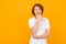 Portret of a red-haired handsome smiling pensive Caucasian teenager guy in a white T-shirt on a yellow background with