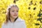 Portret of smiling little girl with handmade hair wreath on yellow Forsythia blossom background