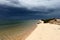 Portugal. Algarve. Ilha deserta. Sand and ocean before storm on dark blue sky background, horizontal view.
