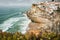Portugal cute town Azenhas do Mar. Atlantic ocean waves rolling to small beach. White chalk houses build on a cliff edge