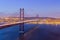 Portugal Travel Destinations. Crossing The Tagus River. Amazing Image of Lisbon Cityscape Along with 25th April Bridge Ponte 25