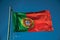 Portuguese flag fluttering in the blue sky