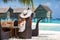 Posh woman sits at a lunch table setup on a beach in the Maldives