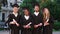 Posing in front of the camera group of graduate students in the college garden they holding their diplomas and wearing