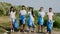 Posing in front of the camera multiethnic group of volunteers after cleaning the beach side they holding big plastic