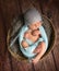 posing newborn baby  with hat on dark background, sleeping baby on furry blanket in small basket, portrait on wooden background