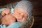 posing newborn baby  with hat on dark background, sleeping baby on furry blanket in small basket, portrait on wooden background