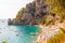 Positano cityscape on rocky landscape, people on the beach, boats are coming and going to the sea tours, scenic promenade on the