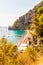 Positano cityscape on rocky landscape, people on the beach, boats are coming and going to the sea tours, scenic promenade on the