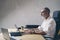 Positive Adult businessman using mobile laptop computer while sitting at wooden table at modern coworking place. .