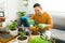 Positive adult man smiling while watering his houseplants