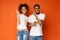 Positive african-american couple listening to music in headphones