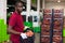 Positive Afro workman stacking boxes with harvested peaches on fruits sorting department