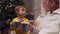 Positive aged man and his grandson drinking tea with cookies