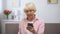 Positive aged woman entering credit card number on smartphone, shopping online