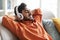 Positive arab guy reclining on sofa, singing songs, using headphones