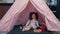 Positive asian toddler girl playing with toys in kids tent