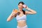 Positive athletic woman in white sportswear holding half of ripe juicy grapefruit and round donut with pink icing, having fun